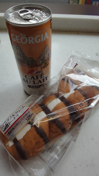 a can of georgia brand cafe au lait and a chocolate-striped eclair filled with whipped cream